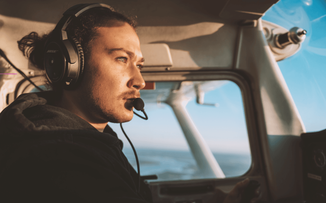 A young pilot with his headset on is flying a small aircraft